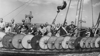 A replica of the Viking ship Gokstad, photographed in Kent, England in 1949. Men dressed as Vikings as sailing it and shields are positioned along its side.