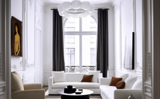 A living room with white walls, ceiling and couches, with rust toned pillows 