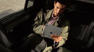 The Apple iPad Pro M5 in the hand of a person riding in a car
