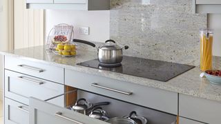 gray kitchen with induction hob with pan and drawer below with a selection of the best induction pans