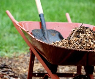 red wheelbarrow with mulch and garden spade