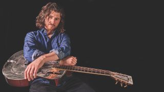 Colour portrait of blues guitarist Dom Martin seated with an Ozark Resonator guitar 