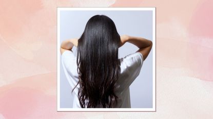 A woman with long shiny hair facing away on a pink watercolour backdrop