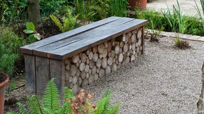 wooden outdoor bench with a log pile underneath