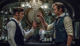 Zac Efron and Hugh Jackman toast with shots in The Greatest Showman.