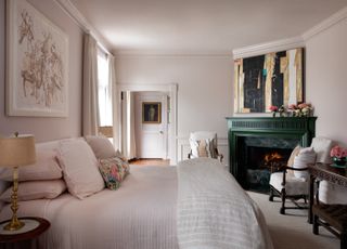 A bedroom with a pink-cream wall tone, and blush bedding