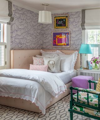 A teenage girl bedroom idea with pale pink upholstered bed and purple and white patterned wallpaper