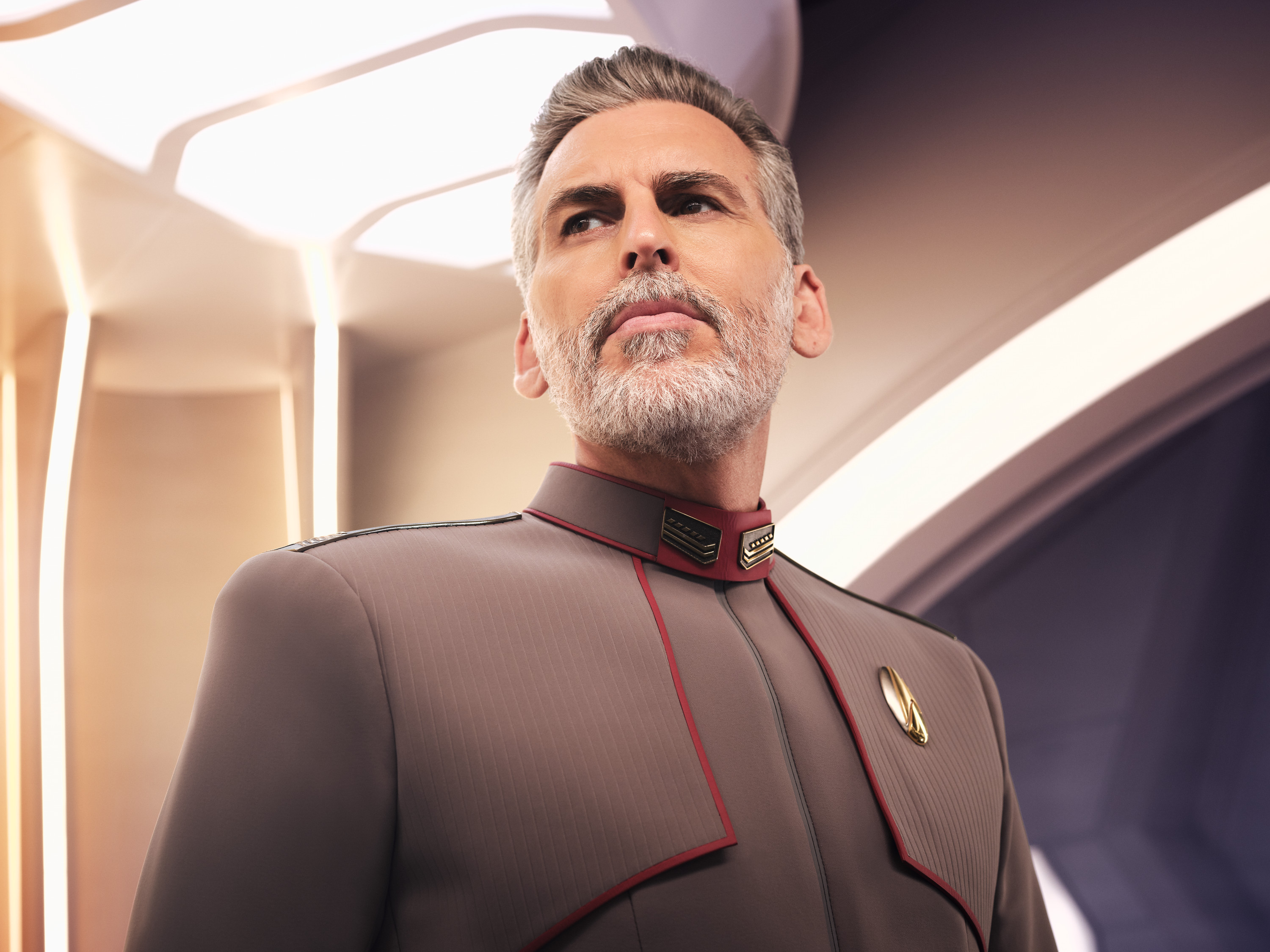 closeup of a gray-haired, bearded man wearing a starship-commander uniform