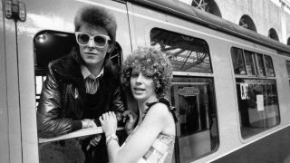 David Bowie leans out of a train window with his wife Angie