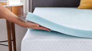 Hand lifting underneath Linenspa mattress topper on bed