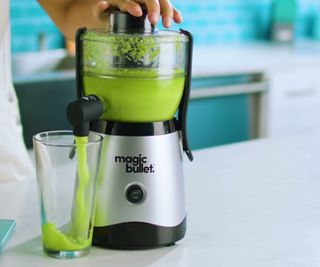 Magic Bullet Mini Juicer making green juice on a white countertop