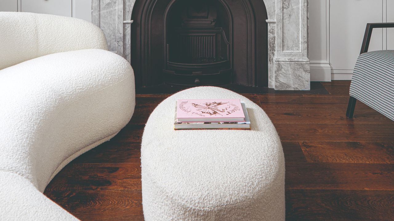 A curved boucle sofa in a living room with a fireplace