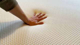 Hand resting on fabric cover of Nectar Premier Hybrid mattress