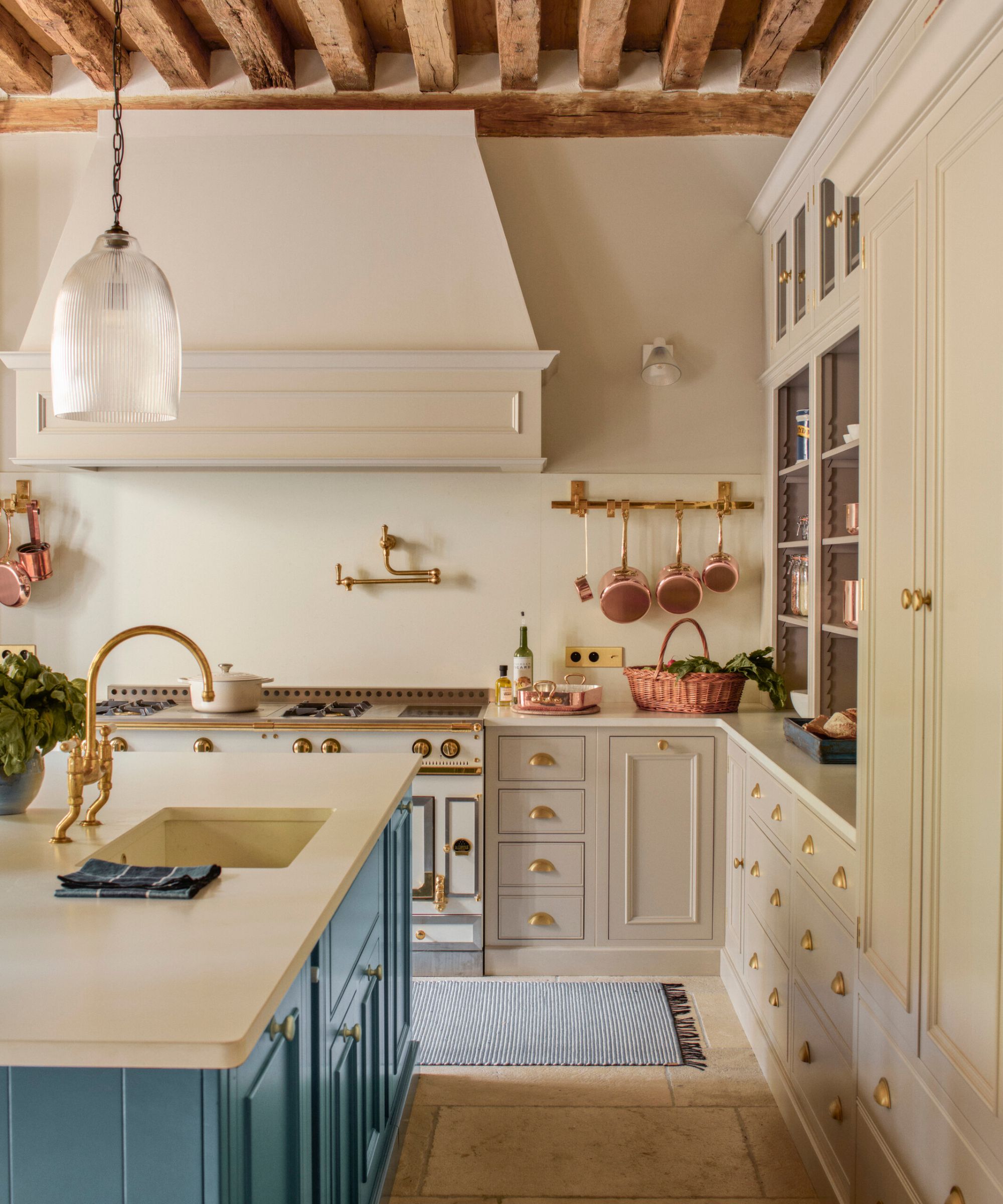 A country kitchen with gray cabinets, a blue island, and a sink on the island