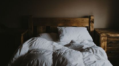 How to get rid of dust mites: A wooden bed with untidy bedding