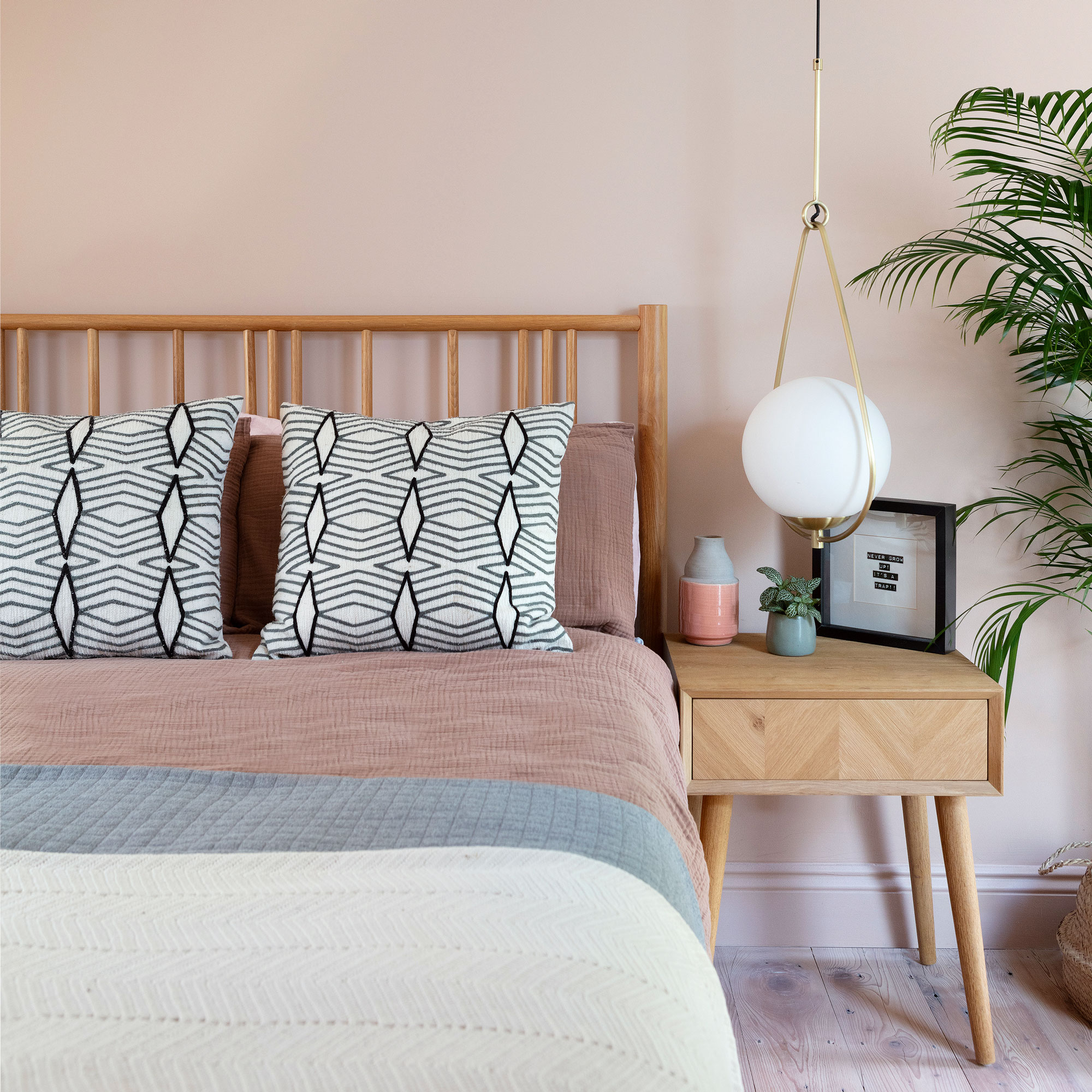 Pink bedroom with wooden bed and black and white geometric pillows
