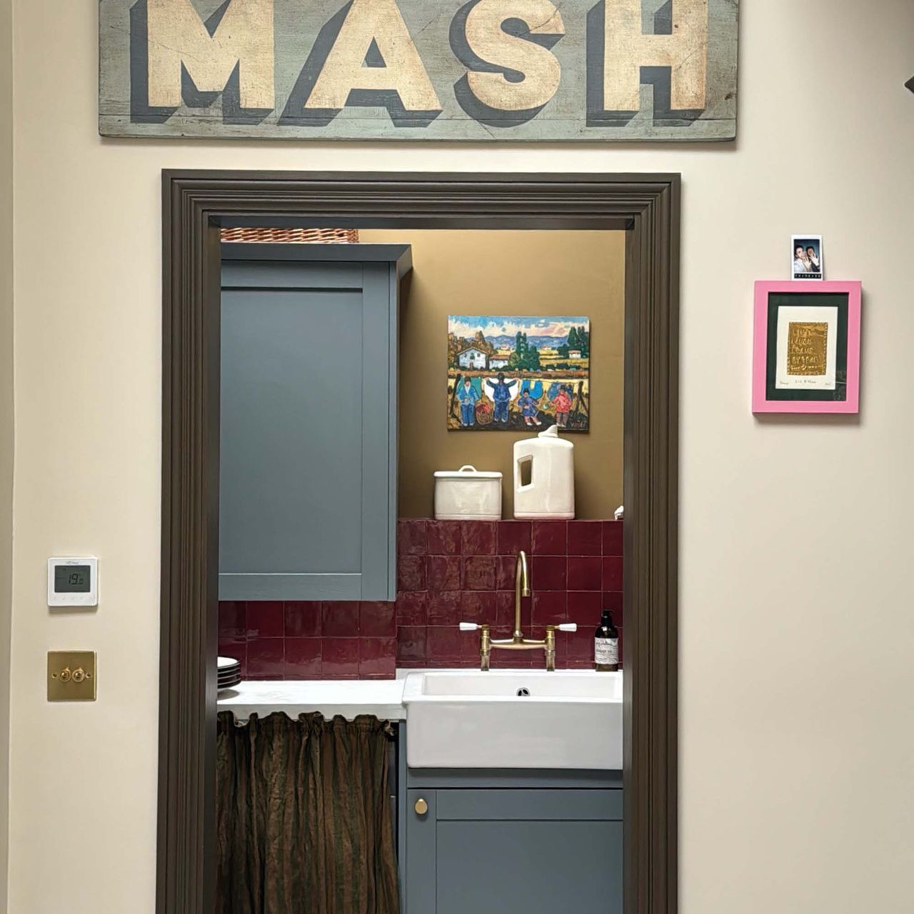 looking through the door at a kitchen with framed art placed on the wall 