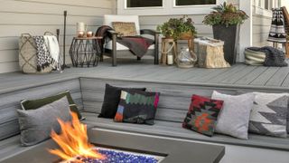 A sunken sitting area made of composite decking material, with cushions and a fire pit