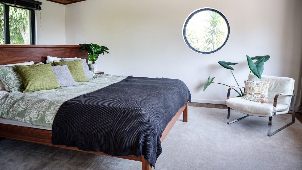 A mid-century modern style bedroom with a round window and a chair in the corner