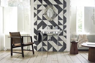 bathroom in trad setting with black and white graphic tiles, art deco vanity, mid century armchair, wooden stools