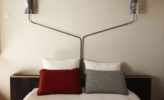 Volkshotel room with cream wall, dark wooden headboard and wall mounted lamps