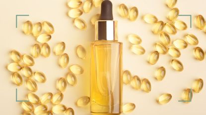 A bottle of Vitamin E oil with capsules behind on a cream backdrop