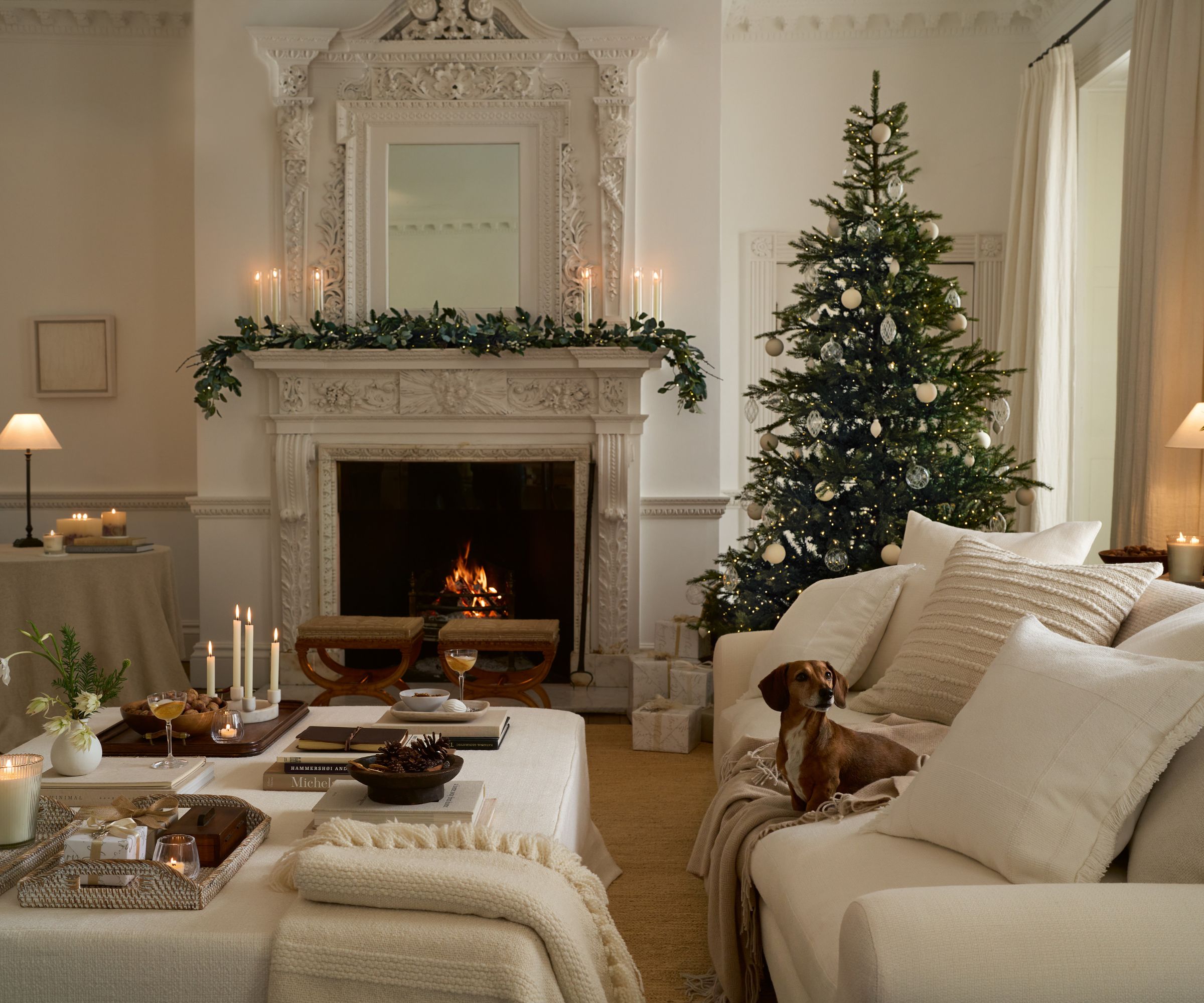 A white living room decorated for the holidays with glass and metal ornaments