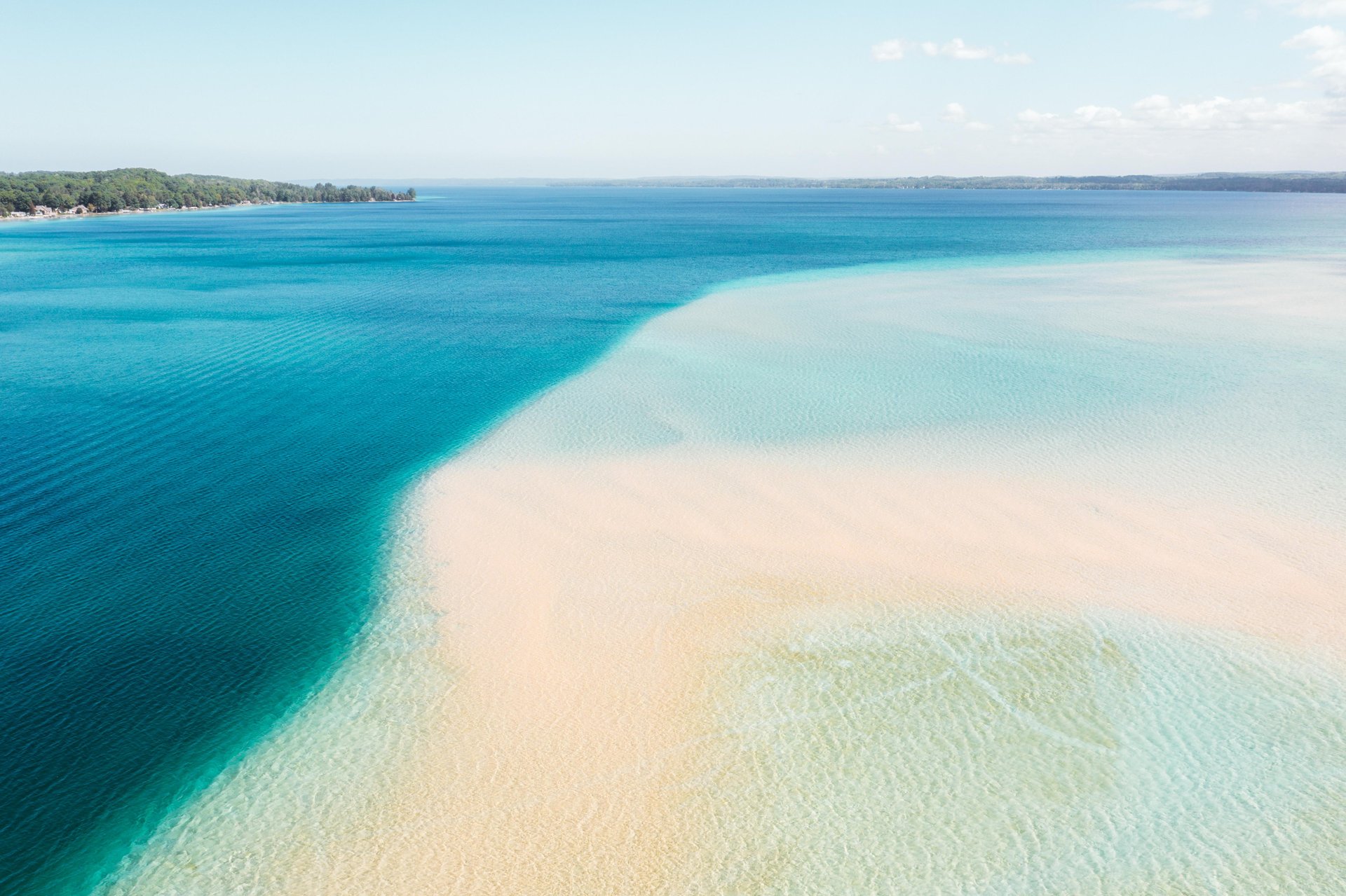 The blue water and white sand of Torch Lake in Michigan