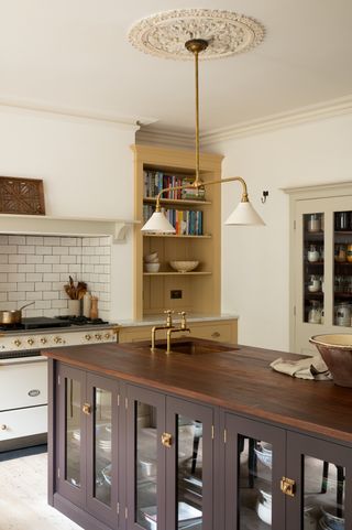 yellow kitchen by devol with light walls and a dark wood kitchen island