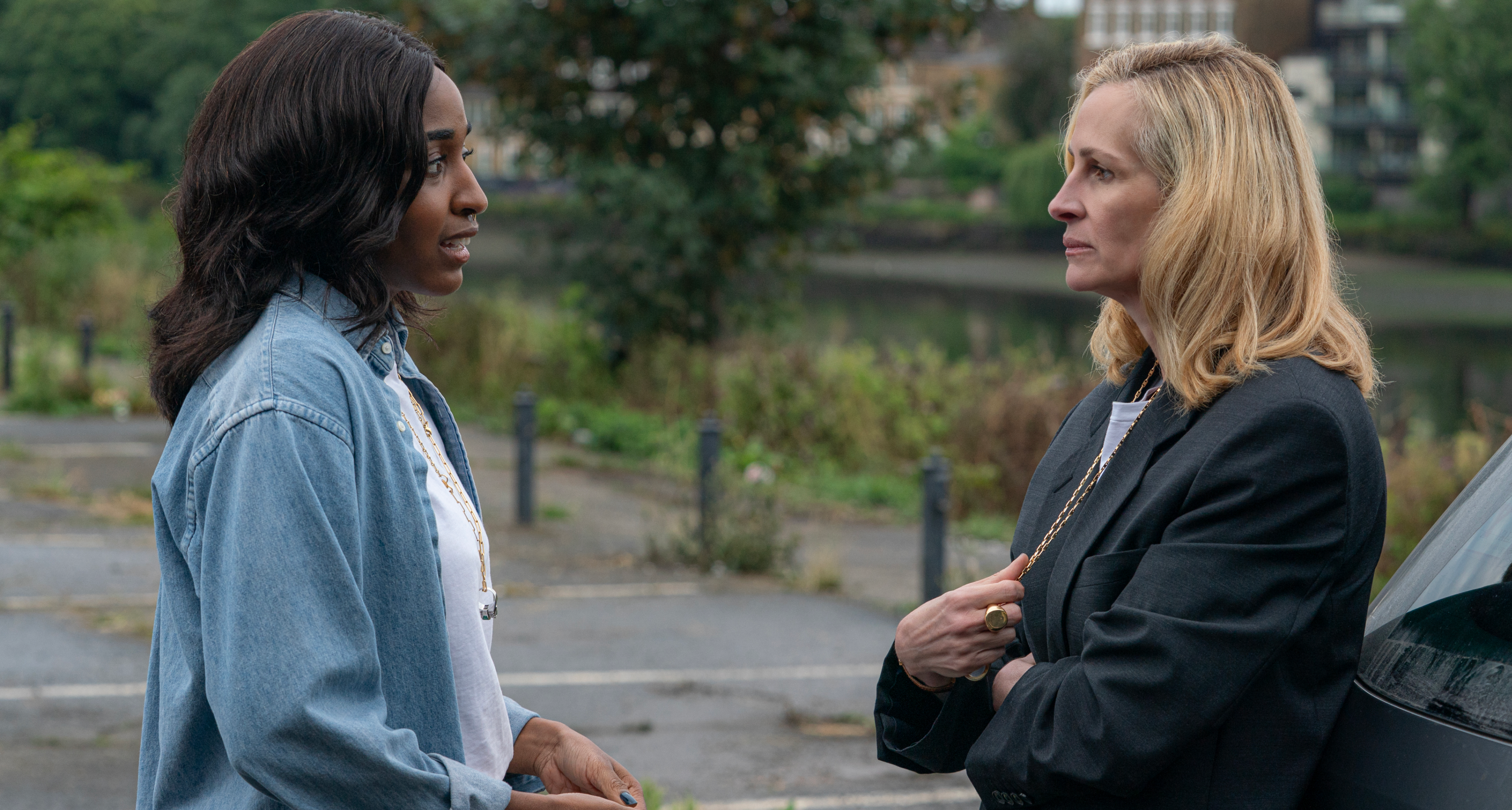 ayo edebiri as maggie wearing a blue shirt speaking to julia roberts as alma in a blazer speaking in a parking lot in after the hunt