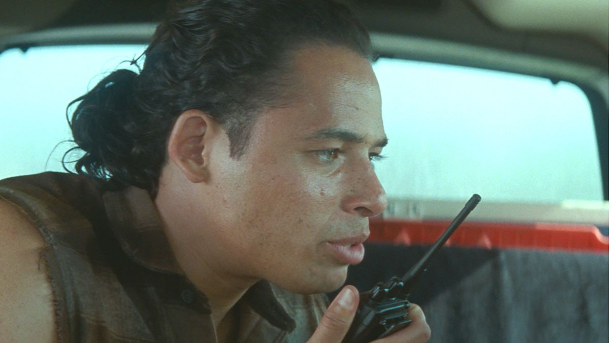 Anthony Ramos sitting in a car looking concerned as he talks to a walkie talkie in Twisters,