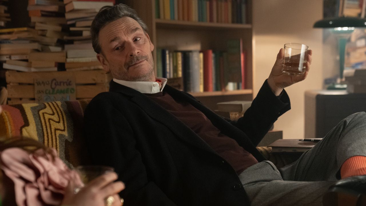 Julian Barratt with a glass in hand on a sofa as George in Extraordinary season 2