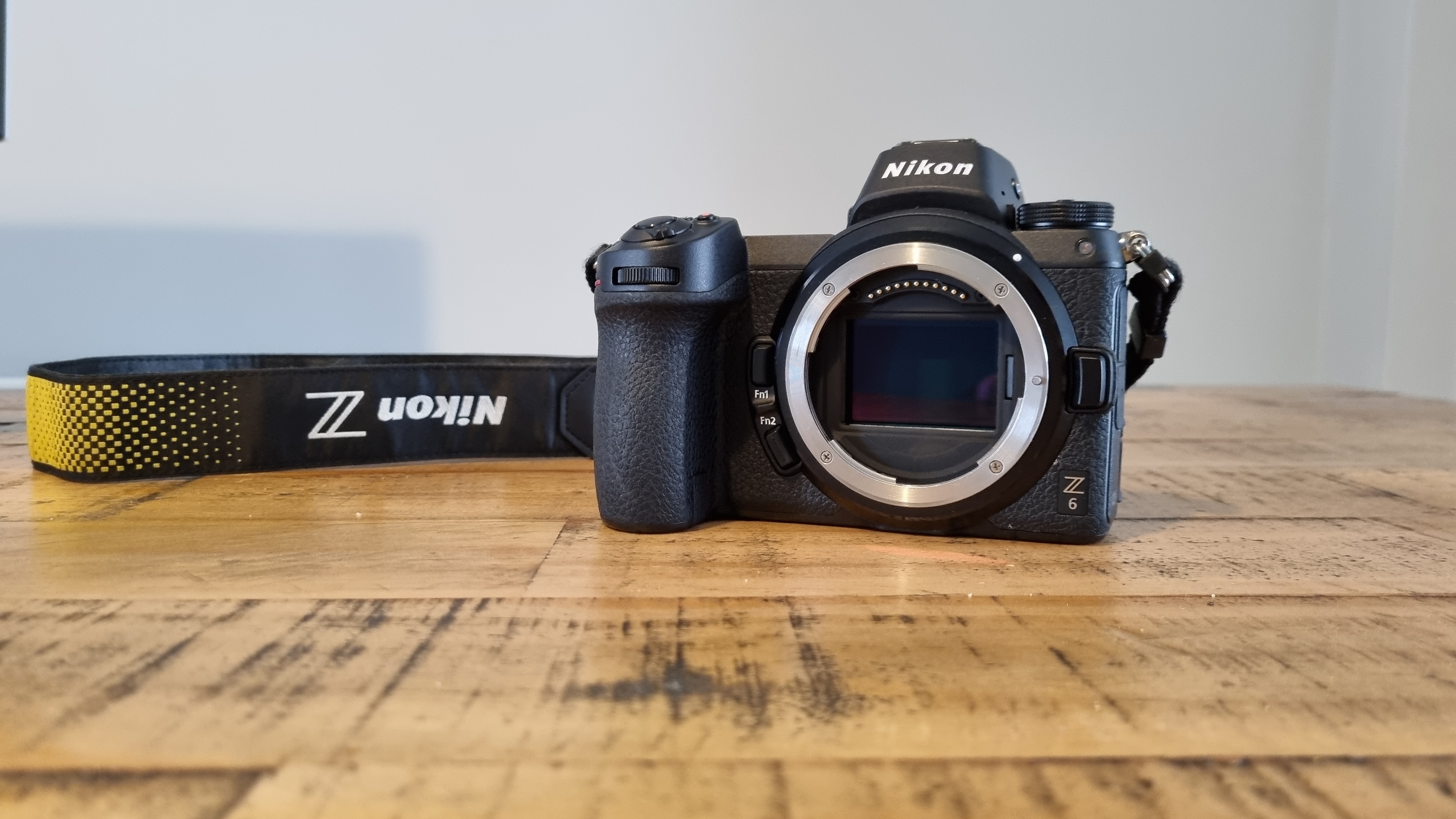 Nikon Z6 camera on a wooden table with the neck strap attached