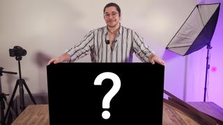 James Artaius standing at a desk with a mystery box bearing a "?" symbol