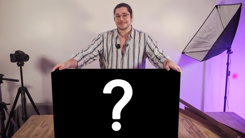 James Artaius standing at a desk with a mystery box bearing a "?" symbol