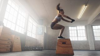 a photo of a woman doing a squat jump in the gym