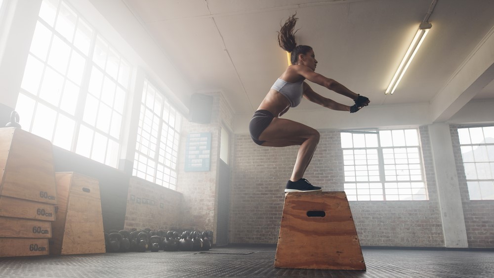 a photo of a woman doing a squat jump in the gym