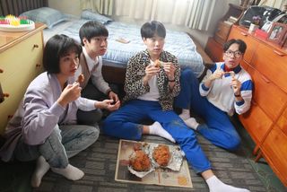 four teenagers eat chicken while sitting on a bedroom floor, in Netflix k-drama 'Reply 1988'
