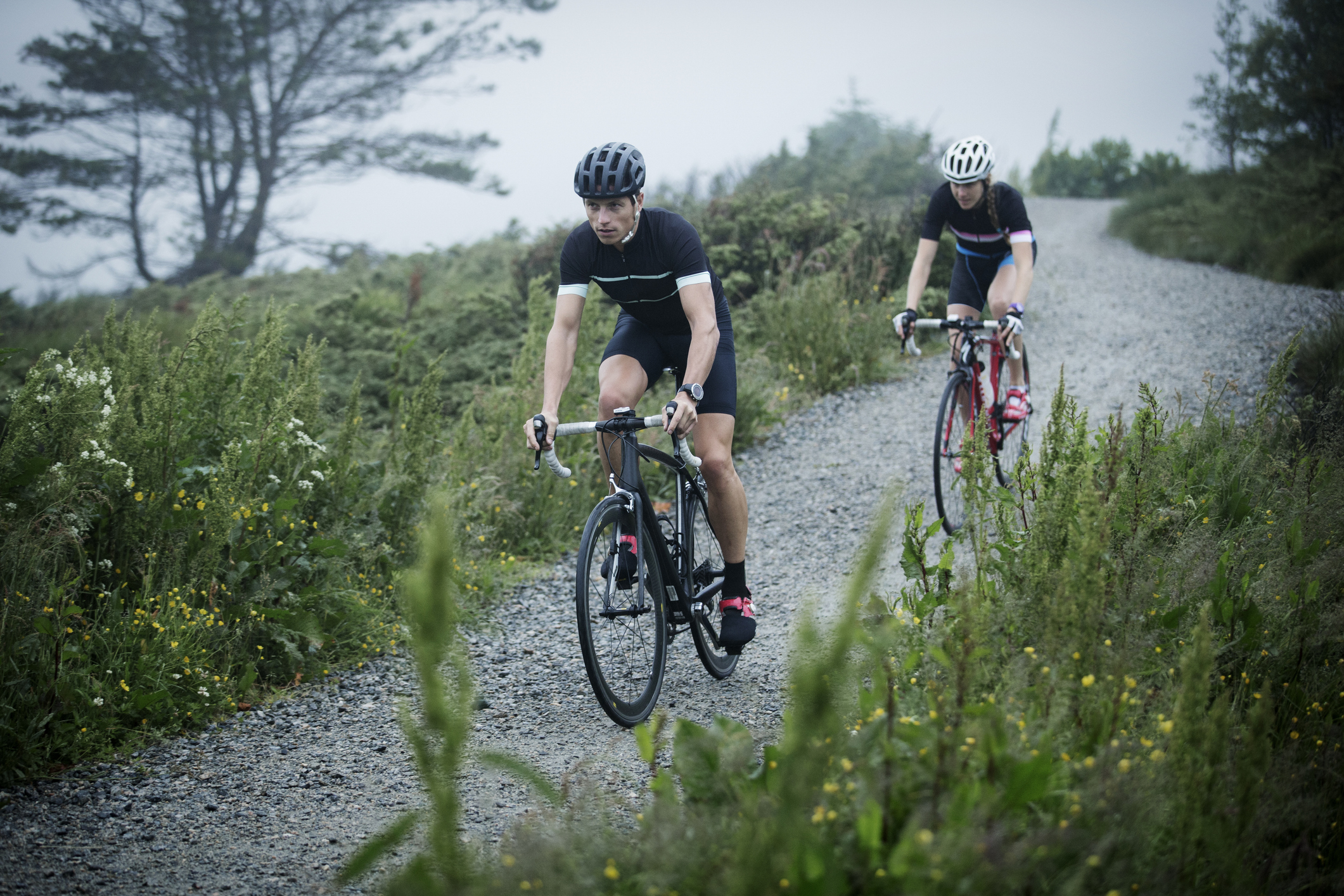 Two people cycle on gravel