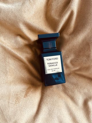 Tom ford tobacco vanille perfume in dark brown bottle on yellow fuzzy background