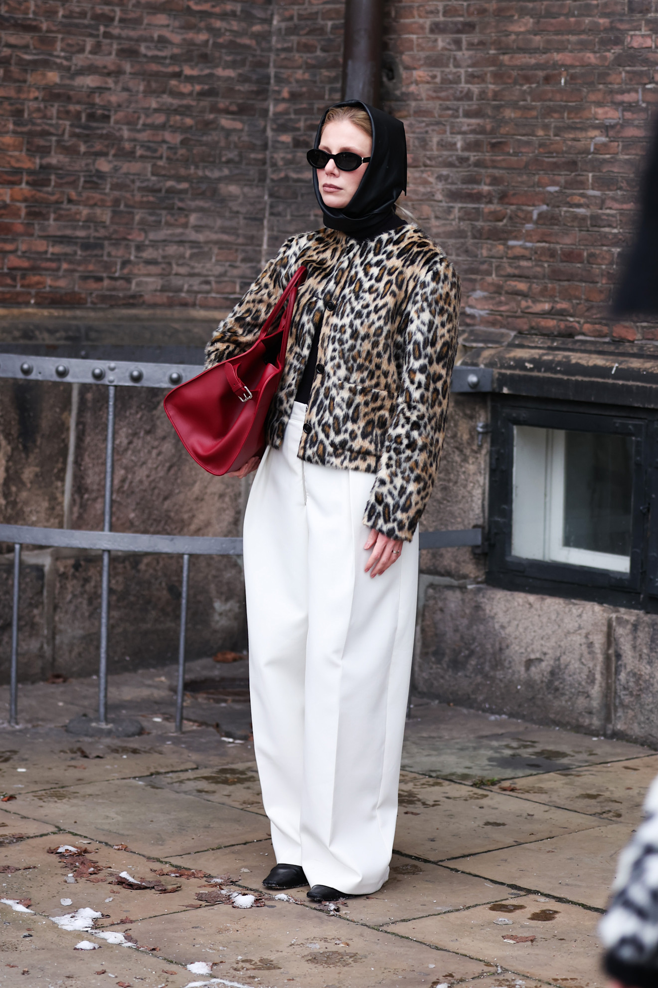 woman wearing white pants, a cheetah jacket and a black hood in Copenhagen