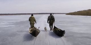 Two trappers walk along a frozen lake in Happy People