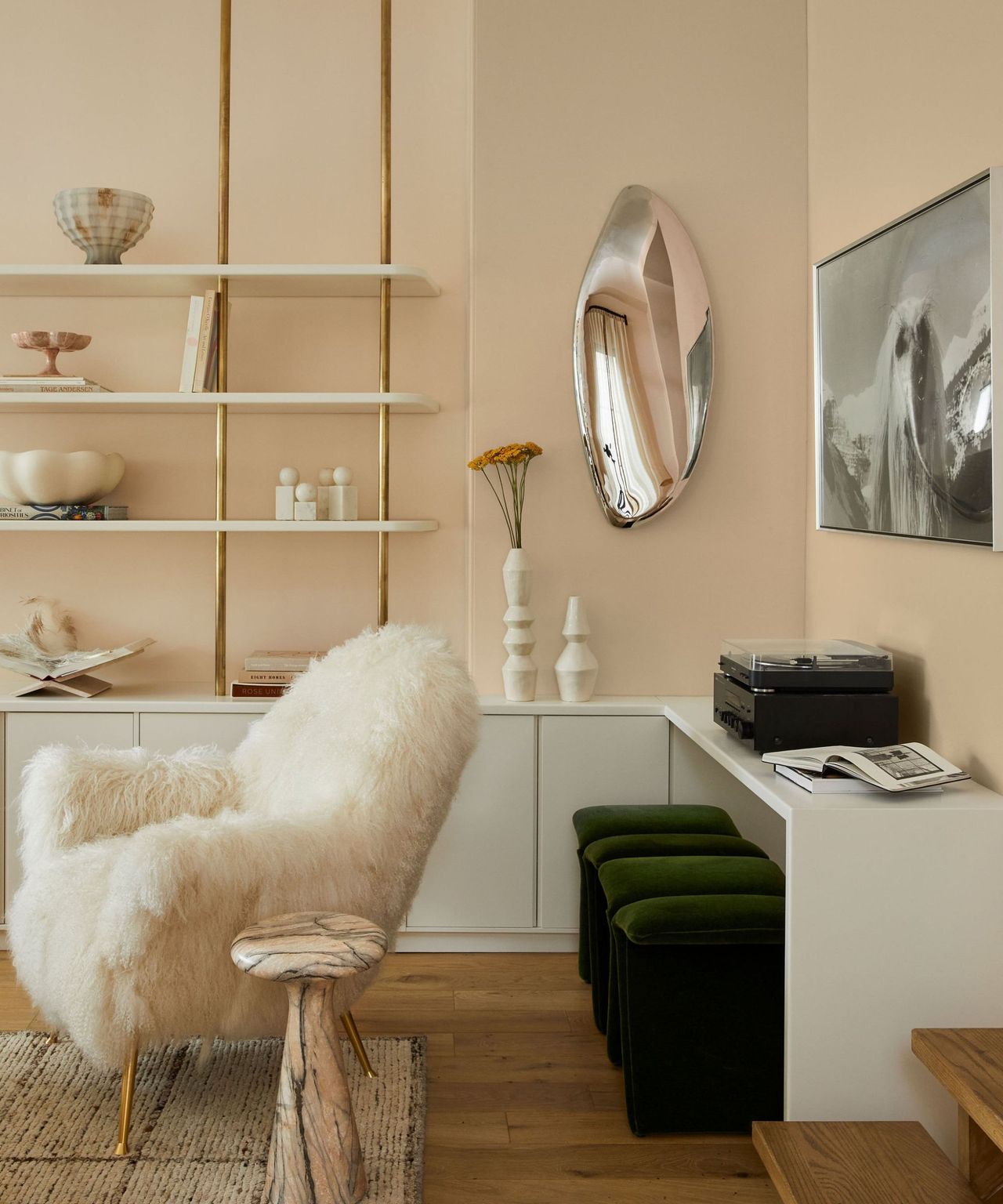 A neutral living room with large black metal windows taking up one wall. There is a large beige sofa with a dog sitting on it and a tree to the left hand side. In front is a large wooden coffee table