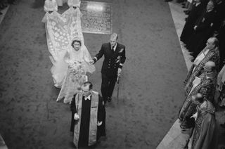 A black and white photo of Princess Elizabeth and Prince Philip walking down the aisle on their wedding day