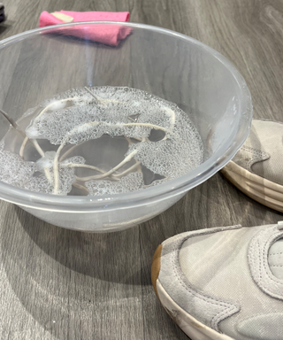 Shoelaces submerged in a mixing bowl of soapy water
