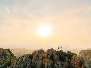 A just married couple on a ridge with the sun behind them