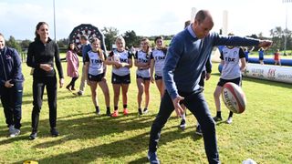 Catherine, Duchess of Cambridge looks on as Prince William, Duke of Cambridge kicks a rugby ball during a visit to the City of Derry Rugby Club on September 29, 2021 in Derry, Northern Ireland.