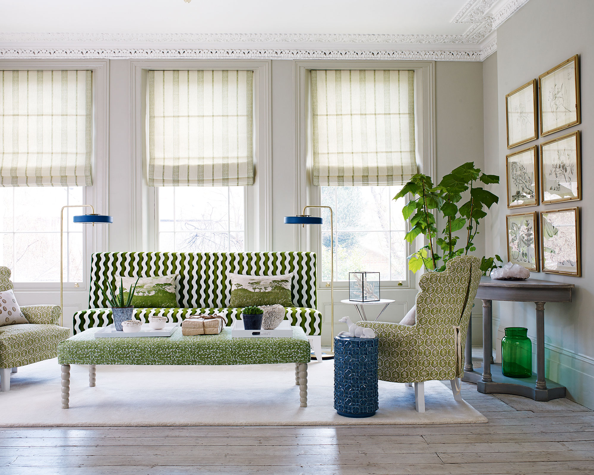 White and green living room idea with striped blinds, green and white patterned sofa and armchairs and a gallery wall.