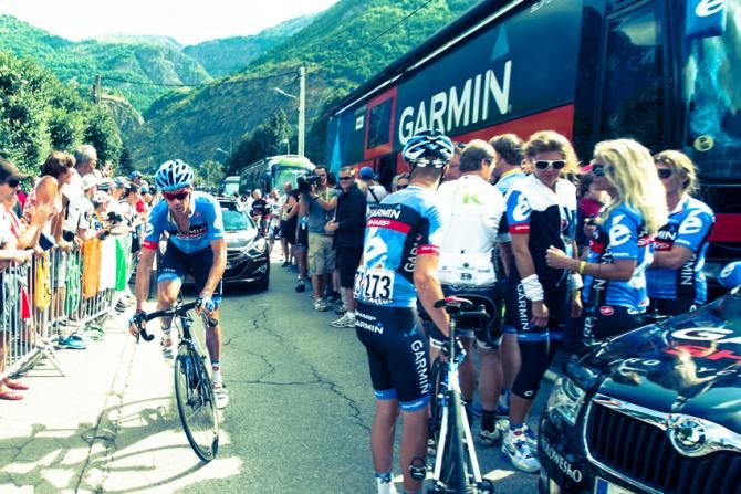 David Millar rides past Tom Danielson and Garmin invitees at the front of their bus at the start of the race.