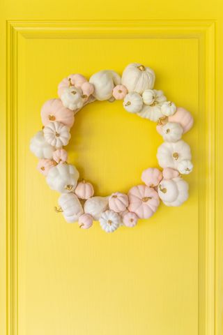 Pastel pumpkins in a wreath on yellow front door